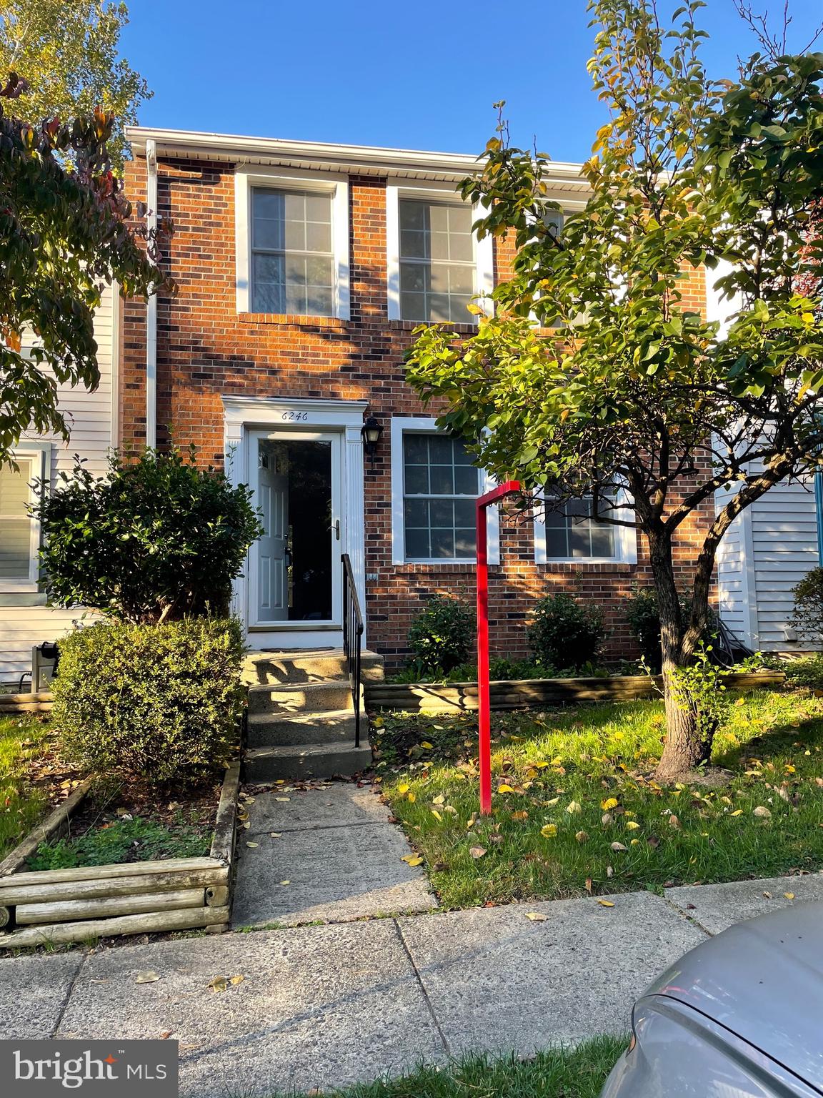 a front view of a house with a yard and tree s