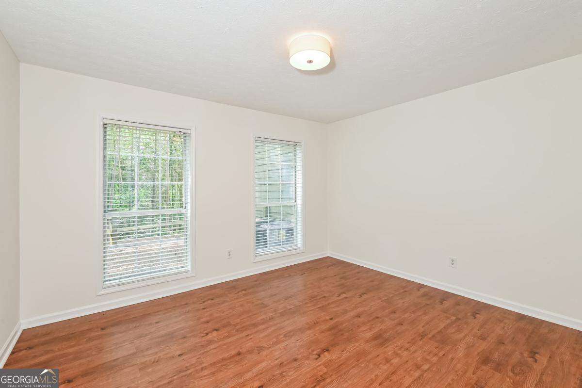 201 Lenox Way Northeast, Unit 201 Atlanta, GA 30324 - Photo 11 of 15 an empty room with wooden floor and windows