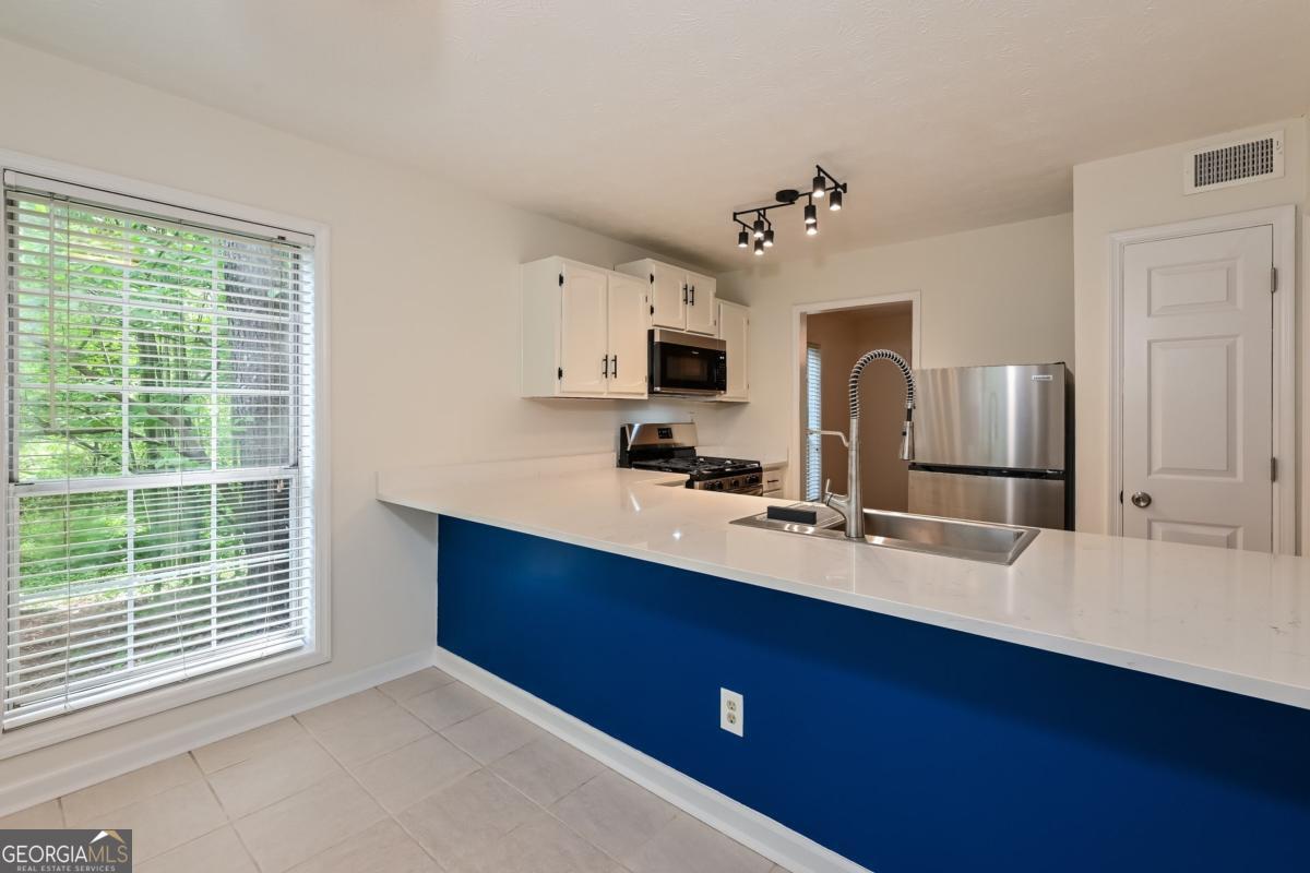 201 Lenox Way Northeast, Unit 201 Atlanta, GA 30324 - Photo 4 of 15 a kitchen with kitchen island a sink stainless steel appliances and window