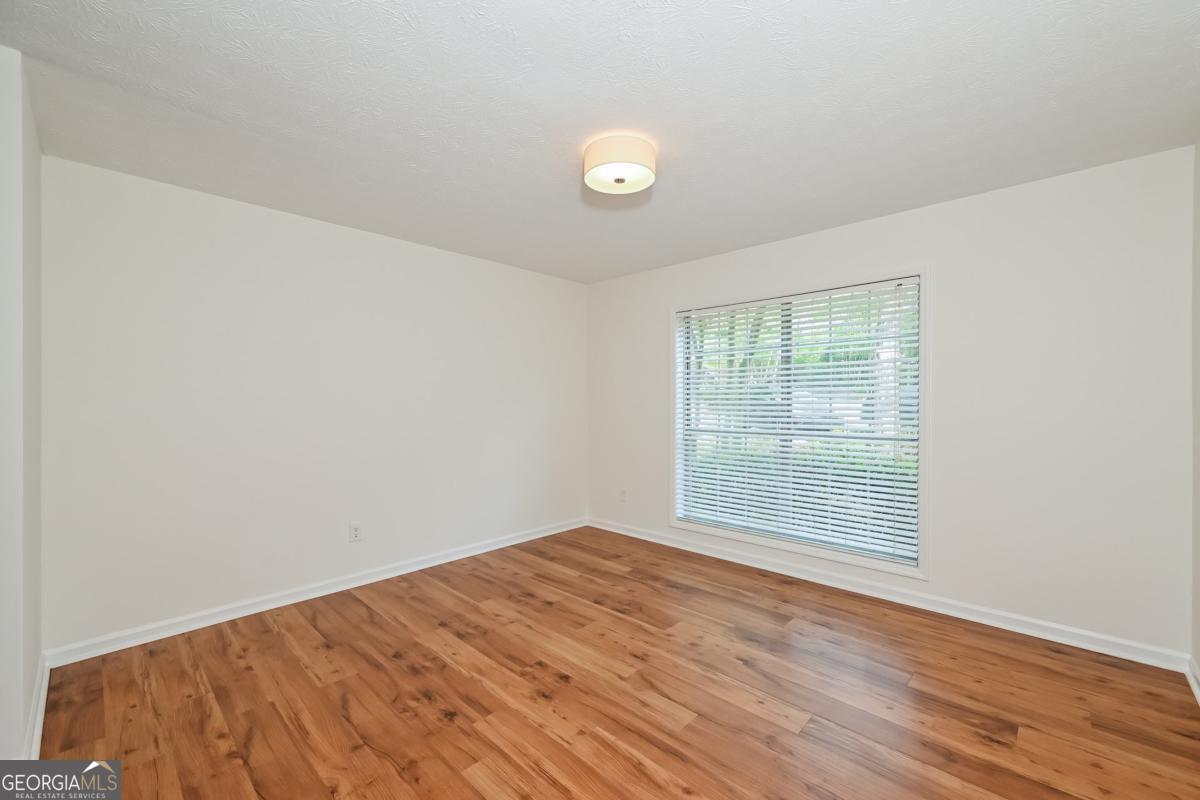 201 Lenox Way Northeast, Unit 201 Atlanta, GA 30324 - Photo 9 of 15 an empty room with wooden floor and windows