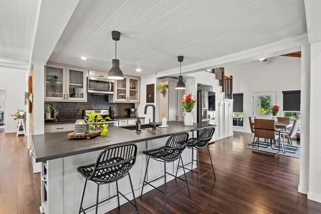 a kitchen with stainless steel appliances kitchen island granite countertop a table chairs and a wooden floor