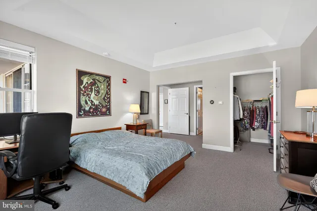 a bedroom with a bed a computer on desk and a dresser