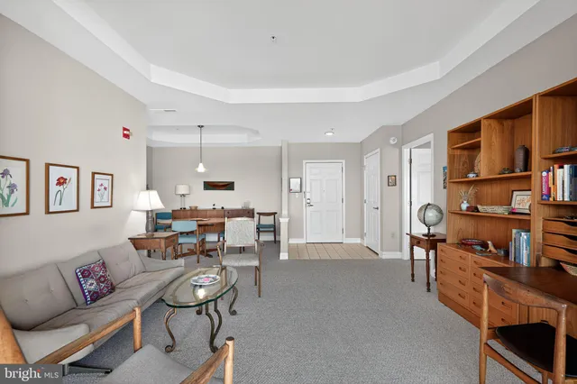 a living room with furniture and a dining table with bookshelf