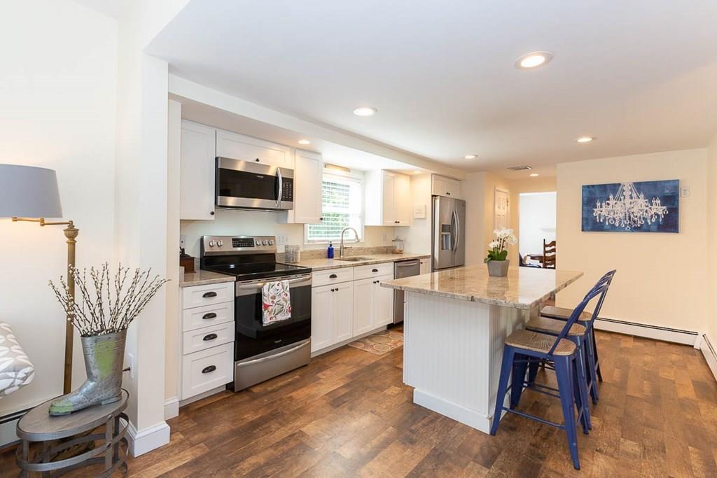 10 Ross Road Lexington, MA 02421 - Photo 16 of 36 a kitchen with stainless steel appliances kitchen island granite countertop a stove top oven a sink a dining table and chairs with wooden floor