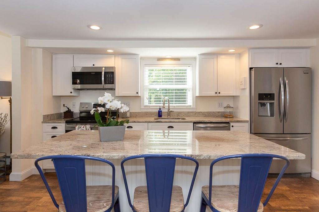 10 Ross Road Lexington, MA 02421 - Photo 17 of 36 a kitchen with stainless steel appliances granite countertop a stove a refrigerator a sink a dining table and chairs