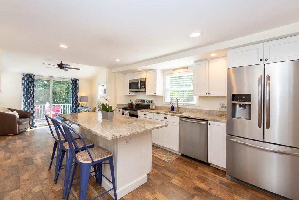 10 Ross Road Lexington, MA 02421 - Photo 18 of 36 a kitchen with stainless steel appliances kitchen island granite countertop a refrigerator a stove a sink a dining table and chairs with wooden floor