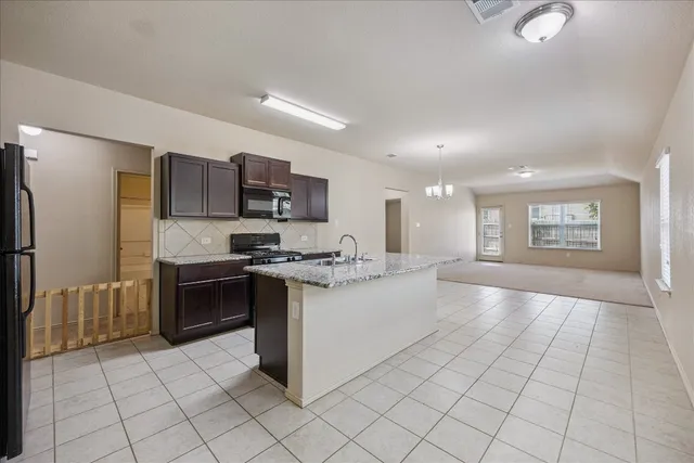 a large kitchen with a large counter top stainless steel appliances and cabinets