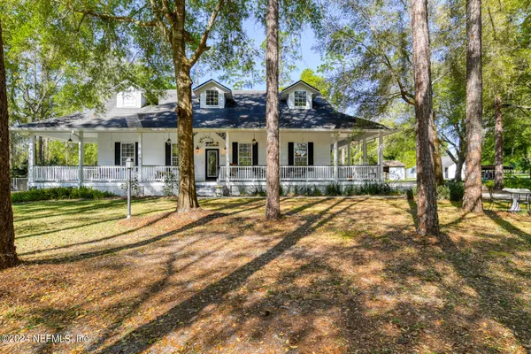 a view of a white house with a large tree and windows