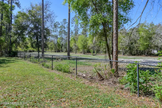 an aerial view of residential house with outdoor space and trees all around
