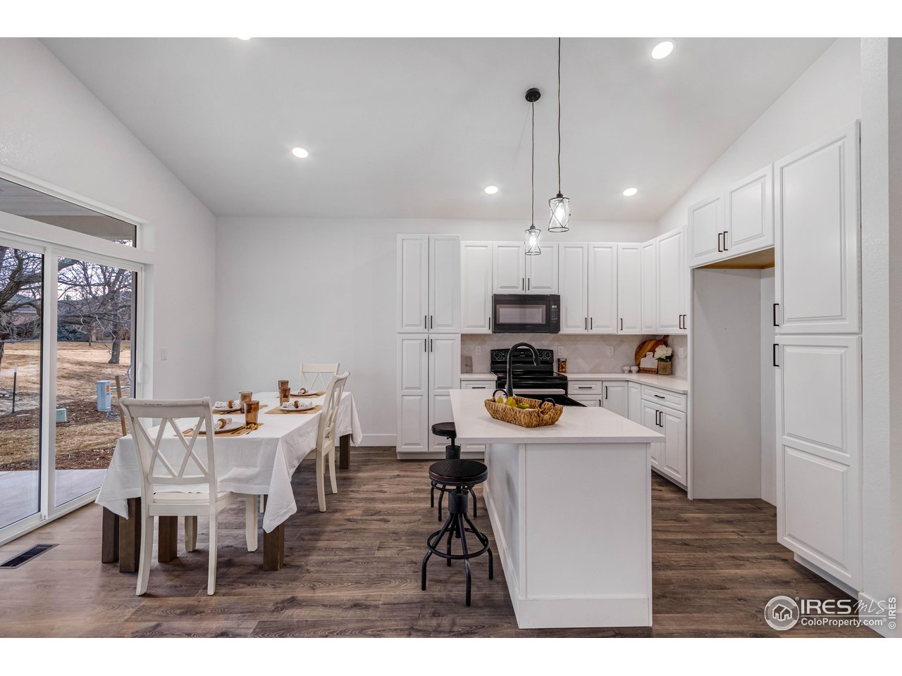 1230 Swainson Road Eaton, CO 80615 - Photo 11 of 29 a kitchen with stainless steel appliances kitchen island granite countertop a dining table chairs refrigerator and sink