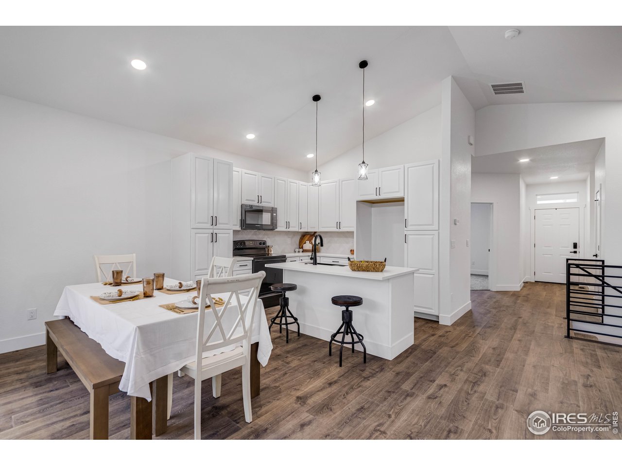 1230 Swainson Road Eaton, CO 80615 - Photo 7 of 29 a kitchen with a dining table chairs wooden floor cabinets and appliances