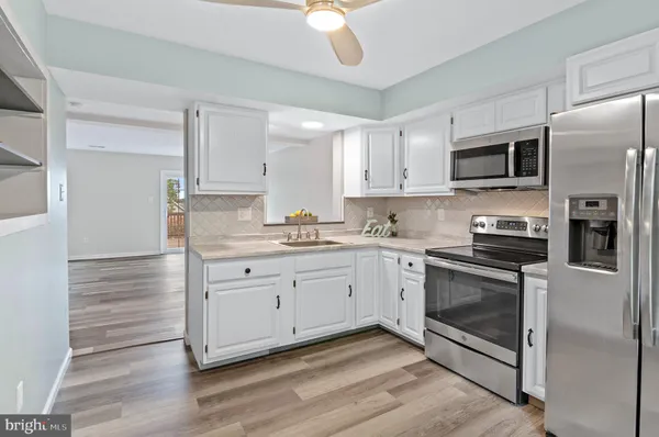 a kitchen with granite countertop white cabinets stainless steel appliances and a counter space