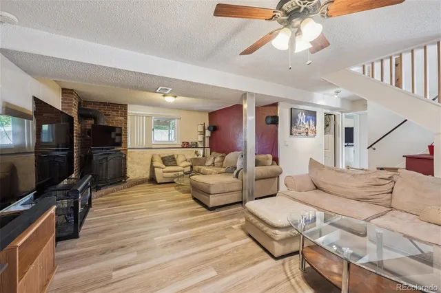 a living room with furniture a flat screen tv and a ceiling fan