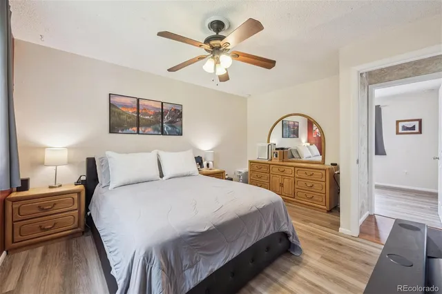 a bedroom with a bed and dresser with wooden floor