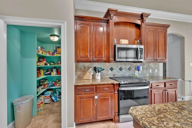 a kitchen with granite countertop a sink a stove and cabinets