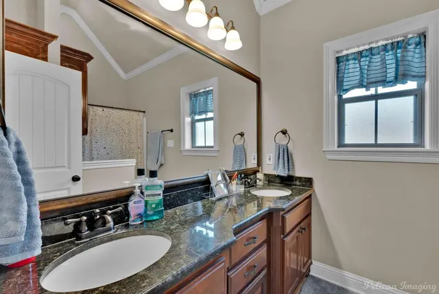 a bathroom with a granite countertop sink a mirror a vanity and a window