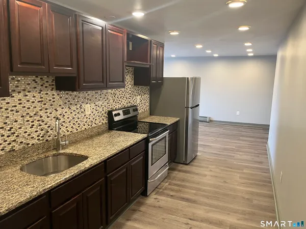 a kitchen with stainless steel appliances granite countertop a sink stove and refrigerator