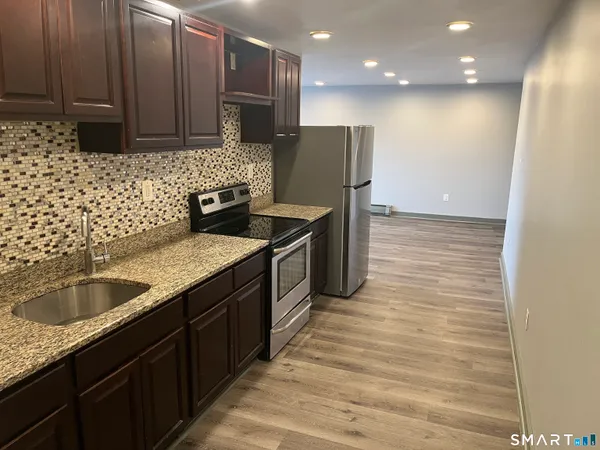 a kitchen with stainless steel appliances granite countertop a sink stove and refrigerator