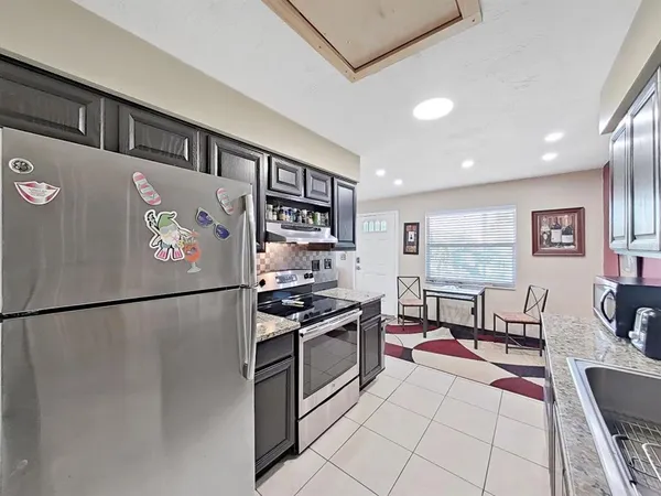 a kitchen with stainless steel appliances granite countertop a refrigerator sink stove and cabinets