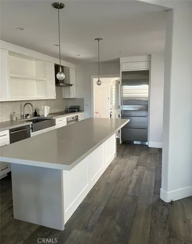 a large kitchen with kitchen island a stove a sink a center island and wooden floor