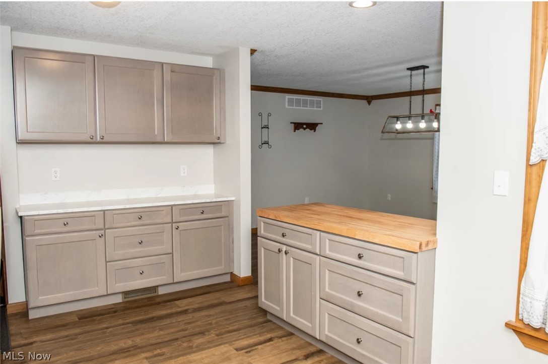 1721 State Road Northwest Warren, OH 44481 - Photo 5 of 37 Kitchen with hanging light fixtures, dark hardwood / wood-style floors, a textured ceiling, wood counters, and ornamental molding