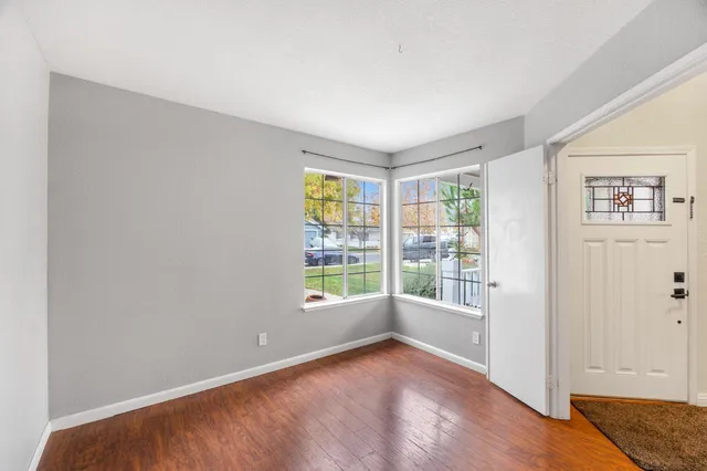 an empty room with wooden floor and windows