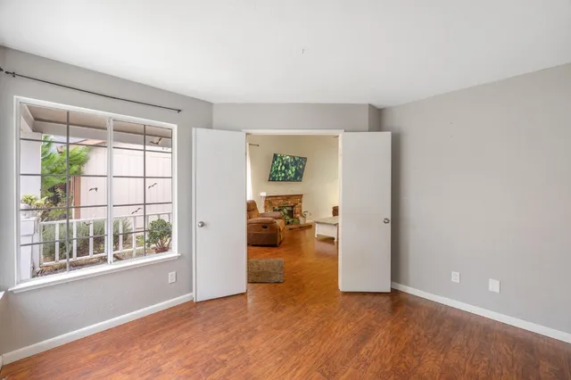 a view of empty room with wooden floor and a window