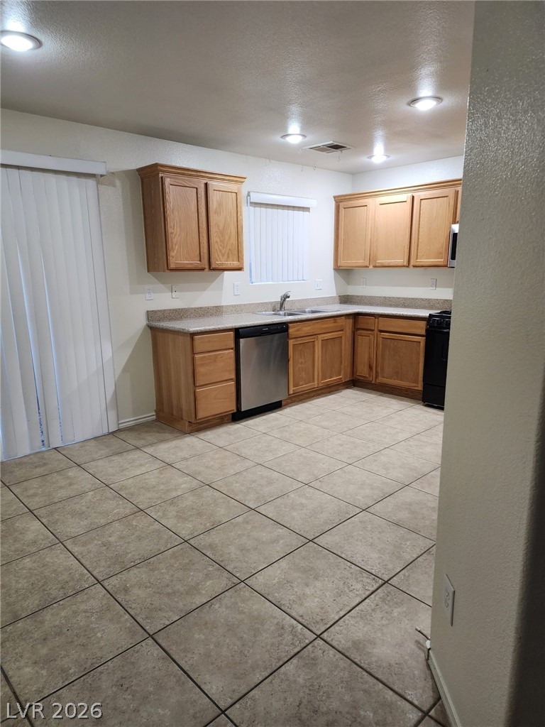 11901 Fairfax Ridge Street Las Vegas, NV 89183 - Photo 8 of 46 Kitchen with a textured ceiling, light countertops, light tile patterned floors, stainless steel dishwasher, and stove