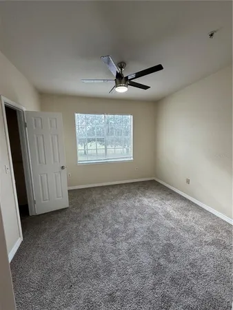 an empty room with closet and a ceiling fan