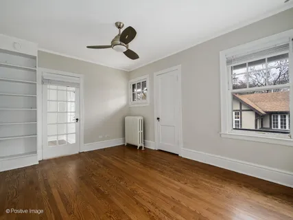 a view of empty room with wooden floor and fan