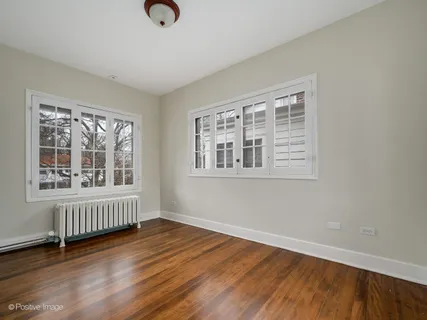 a view of an empty room with wooden floor and windows