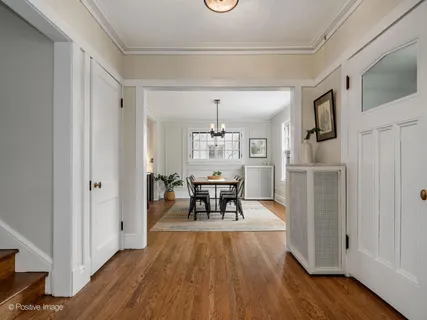 a dining room with wooden floor a chandelier a wooden table and chairs