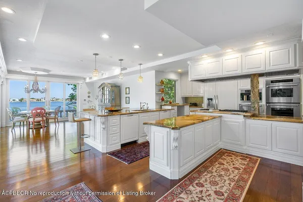 a large white kitchen with lots of counter top space and stainless steel appliances