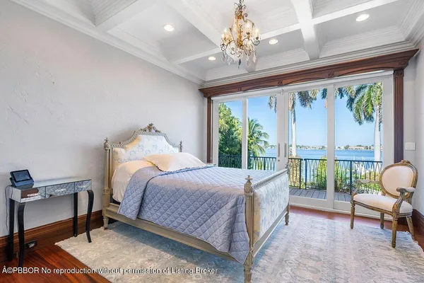 a bedroom with a bed a chandelier and a large window