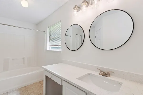 a bathroom with a sink a bathtub and a mirror