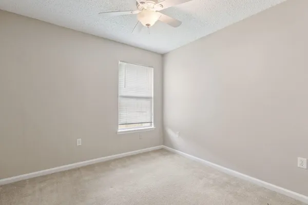 an empty room with a window and a chandelier fan