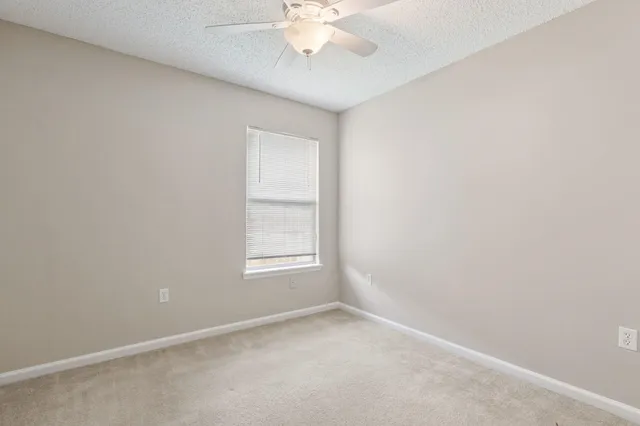 an empty room with a window and a chandelier fan
