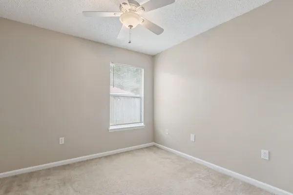 an empty room with windows and fan