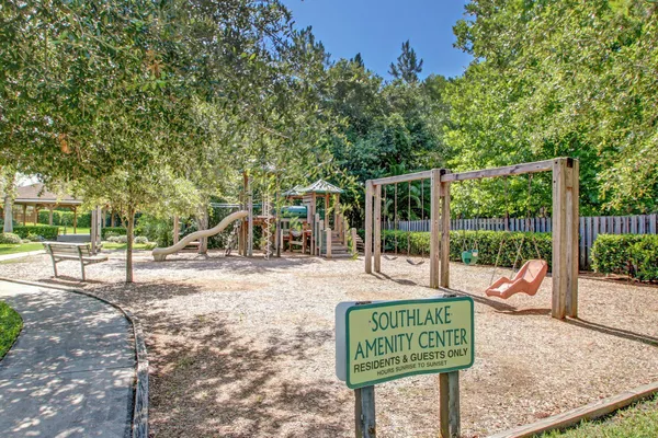 a view of a park that has a sign board large trees