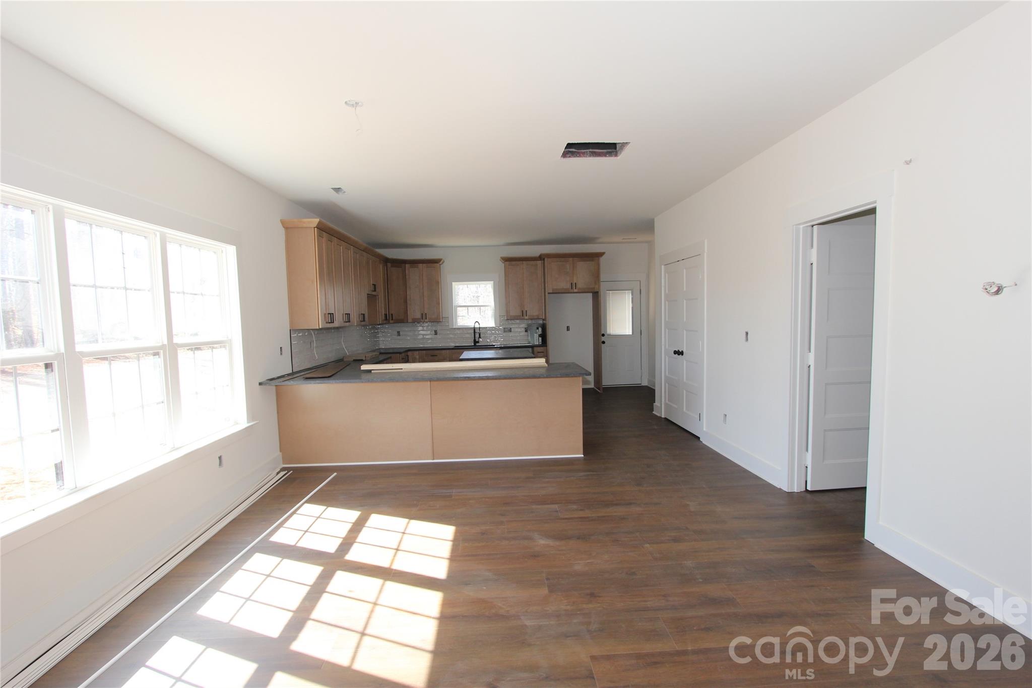 155 Rudisill Road Lincolnton, NC 28092 - Photo 5 of 15 a large kitchen with kitchen island granite countertop a stove a sink a refrigerator and white cabinets with wooden floor