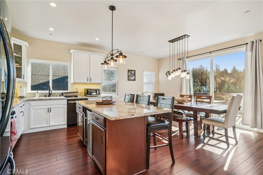 26845 Modoc Lane Lake Arrowhead, CA 92352 - Photo 14 of 56 a open kitchen with stainless steel appliances granite countertop a stove a sink dishwasher a dining table and chairs with wooden floor