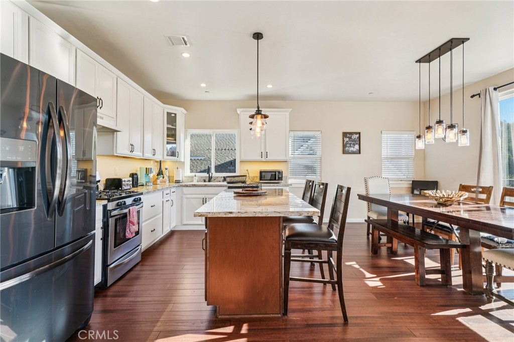 26845 Modoc Lane Lake Arrowhead, CA 92352 - Photo 17 of 56 a kitchen with stainless steel appliances granite countertop a refrigerator a stove a sink dishwasher a dining table and chairs with wooden floor