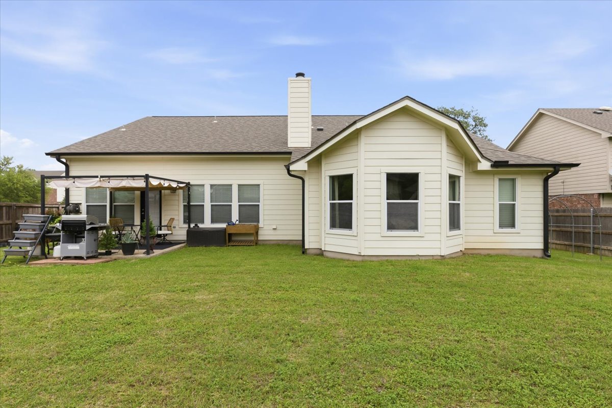 2501 Aspen Meadow Road Leander, TX 78641 - Photo 27 of 30 Expansive green lawn with a cream-colored siding exterior, dark shingle roof, and a bay window extension