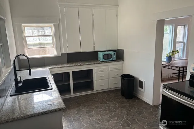 a kitchen with granite countertop a stove a sink and a microwave