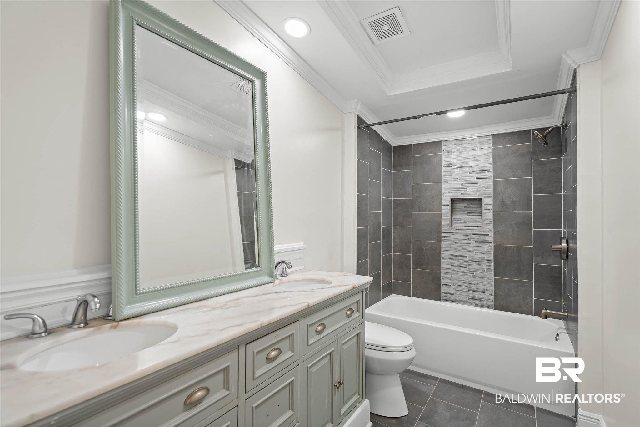 9230 McLeod Road Mobile, AL 36695 - Photo 18 of 20 Bathroom featuring a double vanity with stone countertop and dual undermount sinks, framed mirror, and a tub/shower combination with tile surround and an accent tile inlay