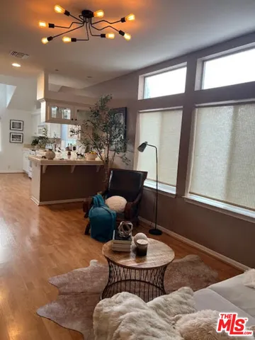 a living room with couches and kitchen view with wooden floor