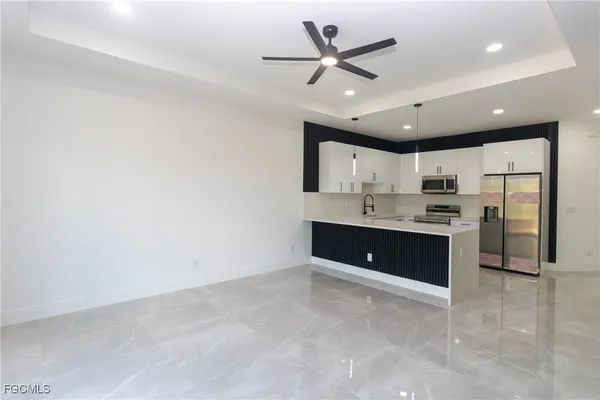 a large white kitchen with a sink stainless steel appliances and cabinets