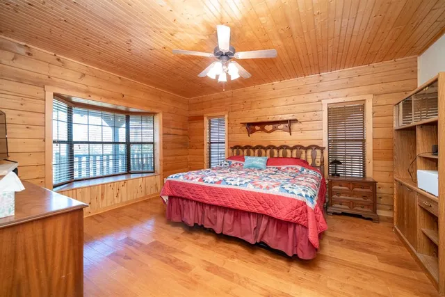 a bedroom with a bed and a large window with wooden floor
