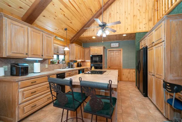 a kitchen with stainless steel appliances kitchen island granite countertop a table chairs in it and wooden floors