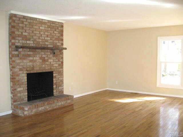 122 Stedwick Place Durham, NC 27712 - Photo 3 of 12 a view of an empty room with wooden floor and a fireplace